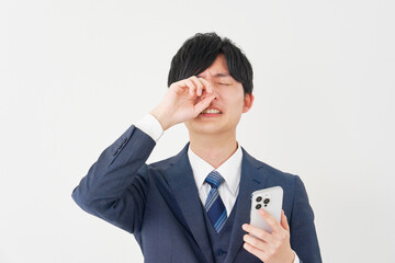 スマートフォンを持って泣くビジネスマン　白背景