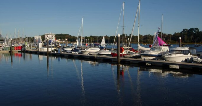 speed up shot of multiple sailing dinghies sailing past moored up motor yachts and out of frame on Lymington river
