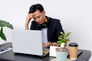 An overwhelmed young employee or businessman exhibiting signs of stress and burnout while working...