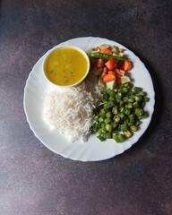 Top view of healthy Indian veg meal rice, dal, vegetables and salad served in a plate.