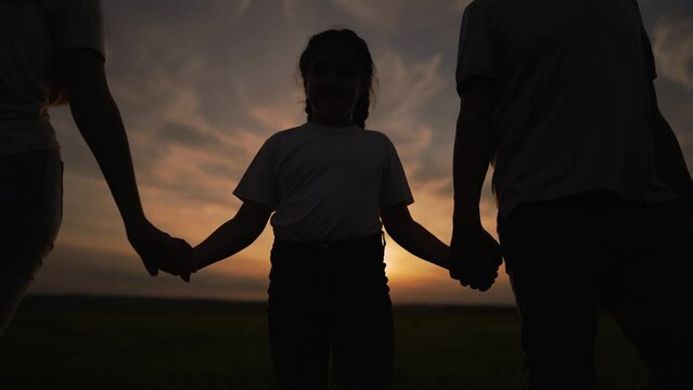 Teamwork. Happy family walking outdoors. Group team walk in nature in the park at sunset. Picnic in the park, family together in nature. People walk on green grass at sunset. Happy family concept