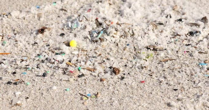 Close-up of microplastics pollution on sandy beach, environmental issue
