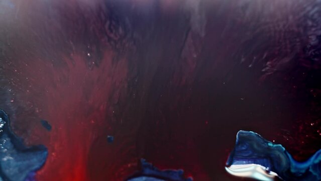 Abstract aerial view of red and blue ink diffusing in water, resembling a cosmic nebula