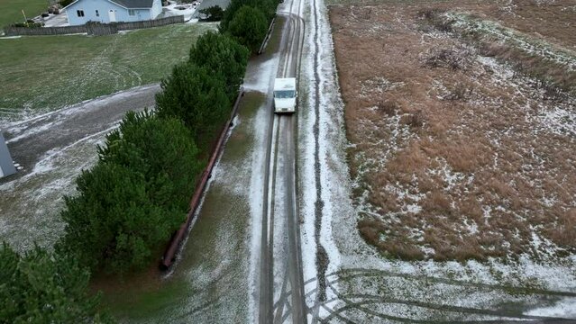 Drone shot of USPS vehicle driving on snow covered rural roads to deliver mail.