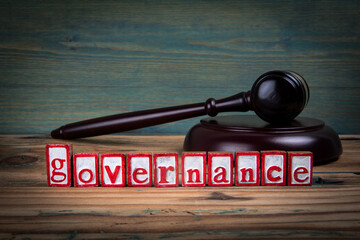 GOVERNANCE. Red alphabet letters and judge's gavel on wooden background. Laws and justice concept