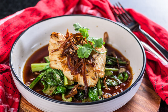 A serve of Grilled Rockling, served with Asian greens and soy sauce.