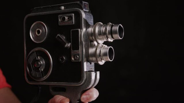 Vintage film movie camera in hand of cinematographer on black background with copy space.