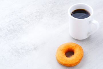 リング状のドーナツと、白いマグカップに入ったコーヒー
