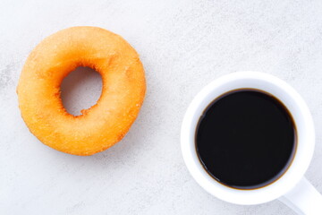 リング状のドーナツと、白いマグカップに入ったコーヒー
