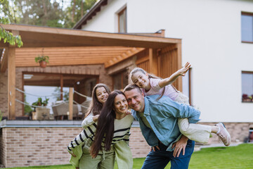 Beautfiul young family standing in front their family home, enjoying together time.