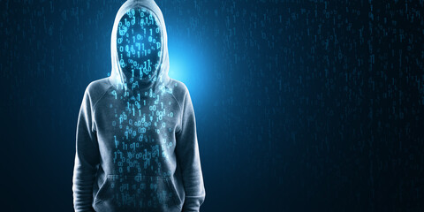 An anonymous hooded figure stands enshrouded in digital binary code, representing cybersecurity and...