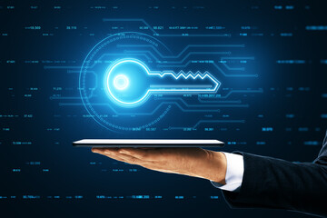 A hand holds a tablet that projects a holographic image of a digital key with technological data and finance graphs in the background