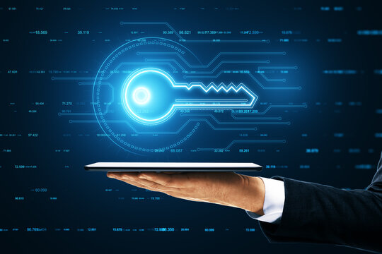 A hand holds a tablet that projects a holographic image of a digital key with technological data and finance graphs in the background