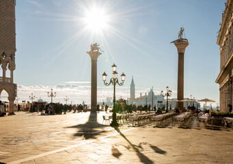 Morgensimmung auf der Piazetta in Venedig, Sonnen Gegenlicht wirft lange Schatten von den Monolithischen Säulen, Blick auf Insel San Giorgio Maggiore.