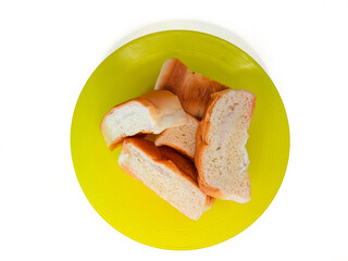 a pile of bread on a yellow plastic plate, isolated on a white background, concept of hunger, poverty and inflation impacting society or humans.
