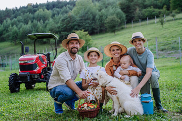 Portrait of farmer family holding harvest basket full of fresh vegetables. Harvesting crops, collecting vegetables on family farm. Concept of multigenerational farming.