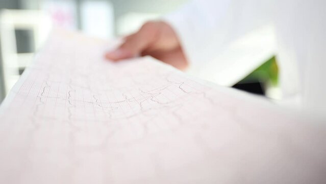 healthcare and medicine concept - close up of male holding clipboard with cardiogram