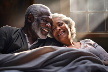 An elderly dark-skinned man and woman laying on top of a bed, embracing in a display of love and affection