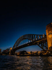 Obraz premium Sydney by night and at sunset is a beautiful sight to behold. The city skyline, complete with the iconic Harbour Bridge, is a picture-perfect view of Australia.