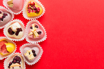 chocolate sweets in the form of a heart with fruits and nuts on a colored background. top view with space for text, holiday concept
