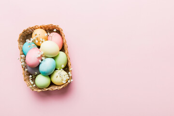 Happy Easter composition. Easter eggs in basket on colored table with gypsophila. Natural dyed colorful eggs background top view with copy space