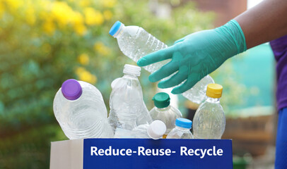 Hand holds used plastic bottle to put in junk bin for recycling. Concept, sorting garbage campaign...