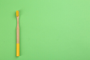 Natural bamboo toothbrush on green background, top view. Space for text