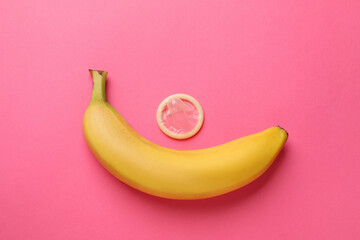 Banana and condom on pink background, flat lay. Safe sex concept