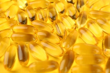 Many vitamin capsules on yellow background, closeup