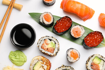 Set of delicious sushi rolls on white background, flat lay