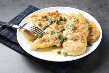 Delicious chicken piccata with herbs served on grey table