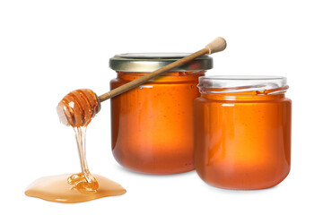 Natural honey dripping from dipper and jars on white background