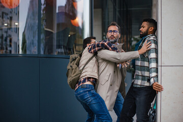 Angry man is aggressive, have conflict with young man, holding him by shirt, screaming, threatening him. Friend helping to end fight. - obrazy, fototapety, plakaty