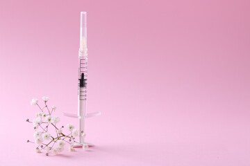 Cosmetology. Medical syringe and gypsophila on pink background, space for text