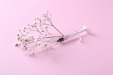 Cosmetology. Medical syringe and gypsophila on pink background