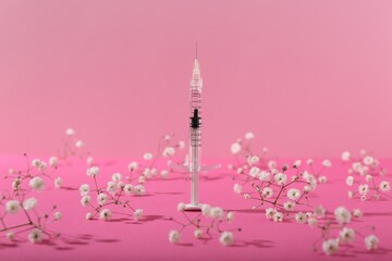 Cosmetology. Medical syringe and gypsophila flowers on pink background