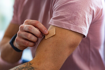 Young man putting nicotine patch on his shoulder, New Year's resolutions, quitting smoking, healthy...