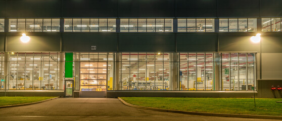 Warehouse facade at night, view of the illuminated warehouse through the windows - 745642995