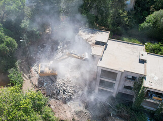  Excavator demolishing barracks for a new construction project. Aerial view.