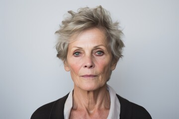 Portrait of a senior woman looking at the camera against a grey background