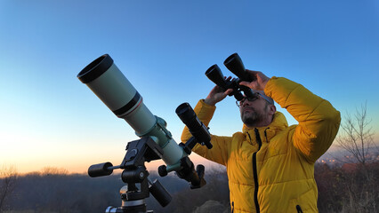 Amateur astronomer observing skies with binoculars and telescope.