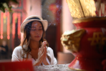 Female tourist praying at a shrine at Chinese temple for blessing, grace and gratitude