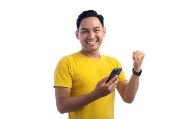 Portrait of excited handsome Asian man using smartphone, gesturing yes with clenched fist, celebrating good news isolated on white background