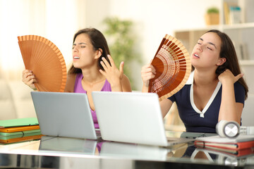 Two students suffering heatwave at home - obrazy, fototapety, plakaty