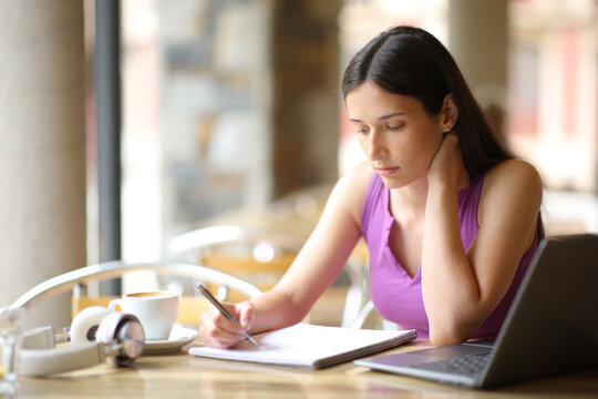 Student studying in a coffee shop reading notes