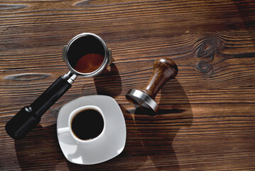 a cup of coffee, a coffee horn and a tamper on a wooden background close-up, copy space