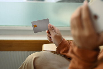Young woman talking on mobile phone holding credit card in hand