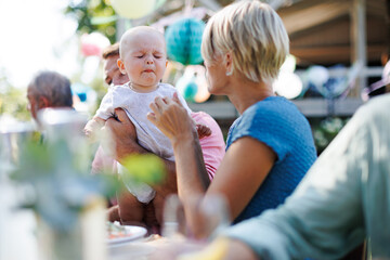 Cute baby eating something sour at summer garden party