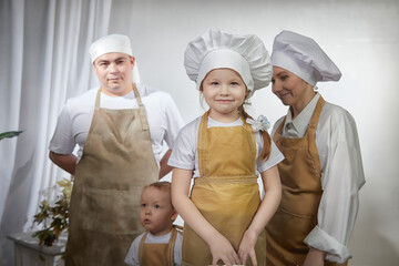 Cute oriental family with mother, father, daughter, son cooking in the kitchen on Ramadan, Kurban-Bairam, Eid al-Adha. Funny family at cook photo shoot. Pancakes, pastries, Maslenitsa, Easter