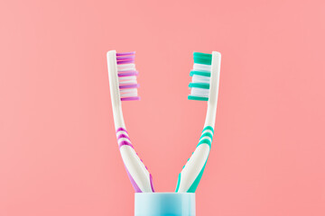 Two manual toothbrushes on a pink background. Front view from low angle.